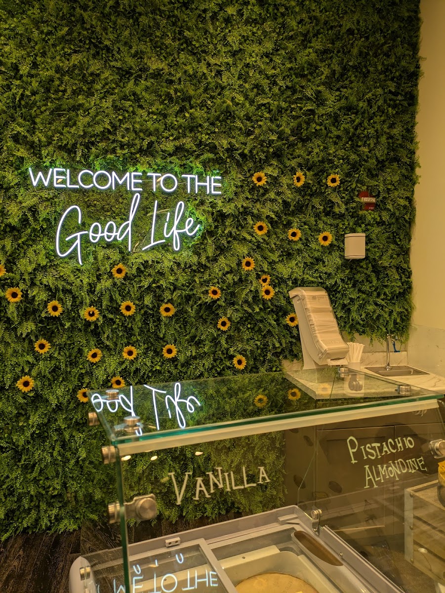 Welcome to the Good Life neon sign on moss wall